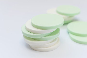 Green and white cosmetic sponges on white background close up. Cosmetology and skin care concept.