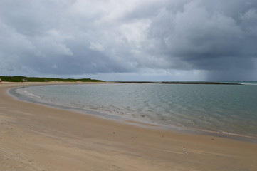 Deserted beach with calm waves under a cloudy sky