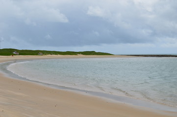Fototapeta na wymiar Deserted beach with calm waves under a cloudy sky