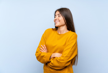 Caucasian young woman over isolated blue wall looking to the side