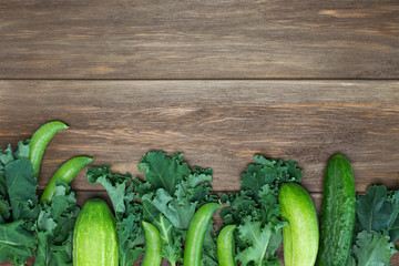 Frame from green salad leaves, peas, cucumbers on wooden background. Vegetables, vegan, harvest, recipe concept. Top view, copy space, flat lay, layout design