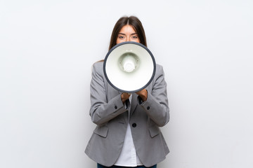 Young business woman over isolated white background shouting through a megaphone