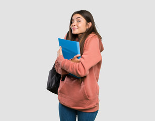 Fototapeta premium Young student woman holding notebooks making doubts gesture while lifting the shoulders over isolated grey background