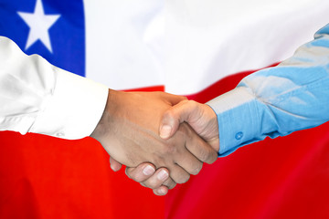 handshake on Chile and Poland flag background.