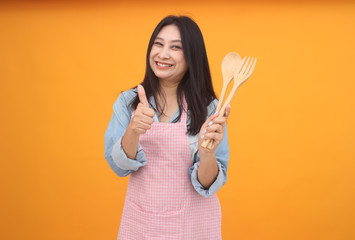Happy Asian woman is cooking with apron for cooking advertise theme on on yellow background.