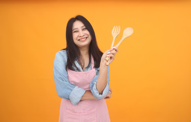 Happy Asian woman is cooking with apron for cooking advertise theme on on yellow background.