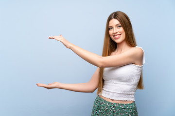 Young woman over isolated blue background holding copyspace to insert an ad