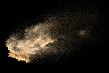 Dry river sand explosion isolated on black background. Abstract sand cloud.Brown colored sand splash against dark background. - obrazy, fototapety, plakaty
