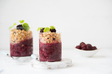Glass of granola with berry yogurt on a light background. Copy space