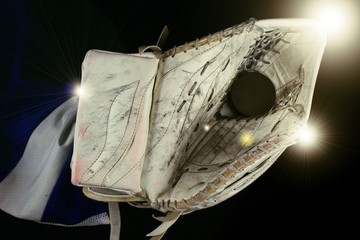 Ice hockey goalie catcher and puck under light.Hockey goalie catcher with black puck  under shining light.