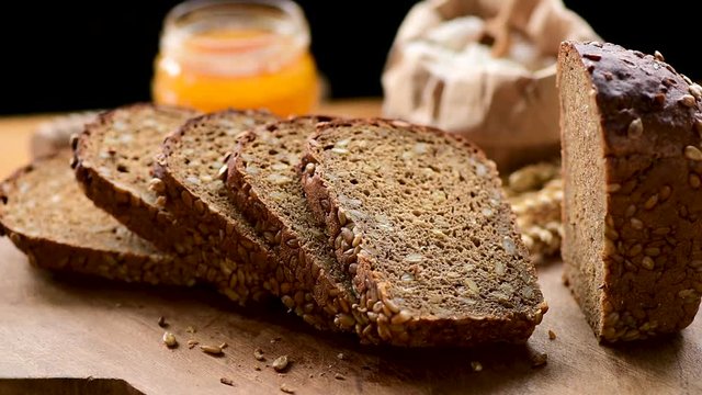 Rotating sliced loaf of rye bread with sunflower seeds on wooden cutting board