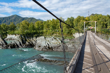Fototapeta na wymiar Suspension bridge over the Katun river in the village of Elekmonar