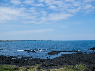Beautiful blue sea with black sand beach and sky of Jeju island in Korean
