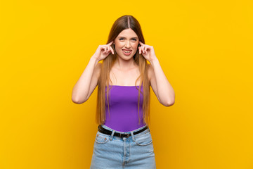 Young woman over isolated yellow background frustrated and covering ears