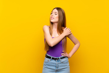 Young woman over isolated yellow background suffering from pain in shoulder for having made an effort
