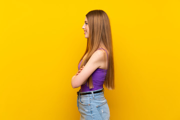 Fototapeta premium Young woman over isolated yellow background in lateral position