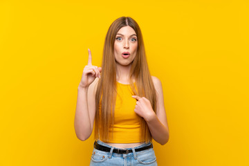 Young woman over isolated yellow background with surprise facial expression
