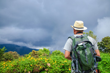 Men travel to visit the high mountains during variable weather.