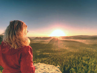 Girl watch Sun rising at horizon. Colorful spring valley