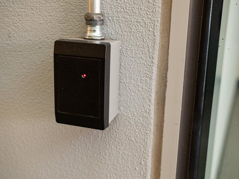 Black keycard reader outside of a entryway with red light