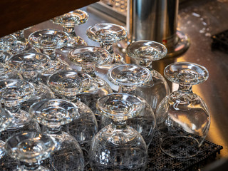 Rows of beer snifters glasses resting on bar ready for serving