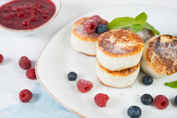 Delicious cheesecakes pancakes, decorated with fresh berries and mint. Horizontal orientation.