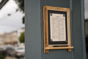 Waitlist filled with names at popular restaurant location hanging outside