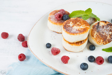 Delicious cheesecakes pancakes, decorated with fresh berries and mint. Horizontal orientation.