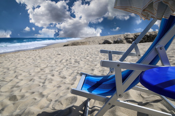 Blauer Liegestuhl und Sonnenschirm an einem Strand, Detailansicht