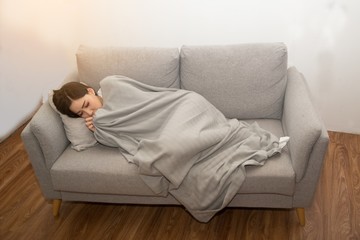 Asian Sick woman covered with a blanket lying in bed with high fever and a flu. 