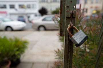 Rusted lock on outdoor gate leading to sidewalk in urban area