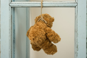 teddy bear hanging on old window