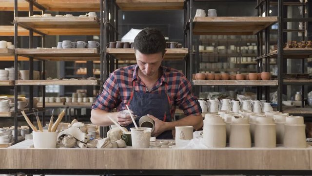 Caucasian male potter making pattern on the vase.