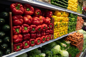 Bell peppers, greens, carrots, cucumbers, lettuce, vegetables in produce section of grocery store
