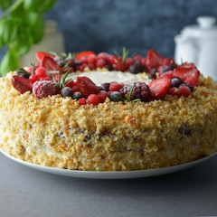 Homemade sponge cake with cream and fresh berries. Carrot and orange cake, decorated with berry. sweet dessert. Whole deliciouse cake. Gray background. Square iamge.