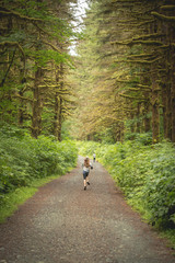girl running down gravel road in woods to catch up 