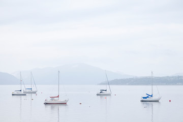 Boats resting in calm tranquil water surround by mountains in Scottish landscape