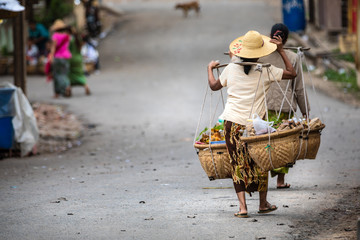 Burmese women who carry food with a typical method. Clothes with characteristic hat of the place....