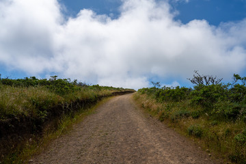 Winding dirt trail road going into horizon with clouds in nature