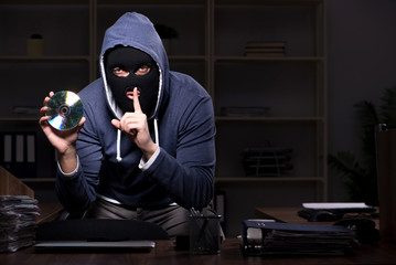 Male thief in balaclava in the office night time