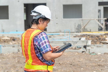 Asian women engineering holds a tablet for use in the inspection of construction sites for accuracy and in accordance with the plan. Concept of Equal rights between men and women