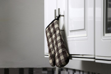 Scottish pattern of heat resistant gloves hanging on the cabinet in the kitchen.