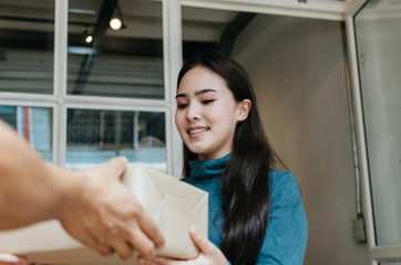 happy young asian woman customer smiling receive parcel post box from home delivery service man at home, express home delivery service, cargo shipping, transport logistics and online shopping concept