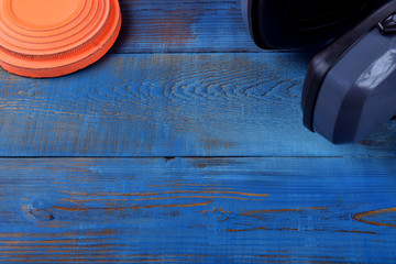 Flying target plate and noise suppression headphones against the blue wooden background. Copy space in the middle