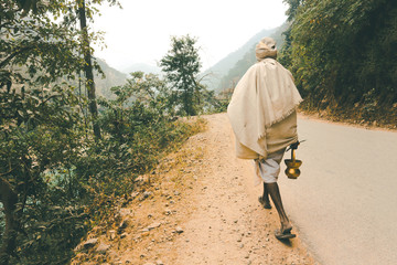 Indian renounced sadhu leaves on the way to the forest. A wandering wanderer with a trident and a...