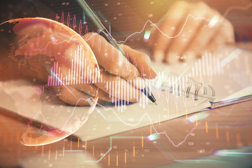 Forex graph on hand taking notes background. Concept of research. Double exposure