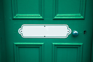 Old blank oval vintage metal painted sign with copy space on a painted cyan wooden background with matching door handle