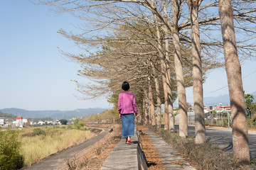 Fototapeta na wymiar Asian woman walk under the tree