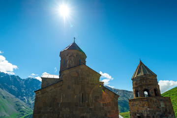 Fototapeta na wymiar Georgia, view of the Trinity Church in the village of Gergeti on a background of mountains on a sunny day