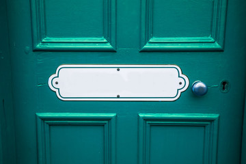 Old blank oval vintage metal painted sign with copy space on a painted blue wooden background with matching door handle